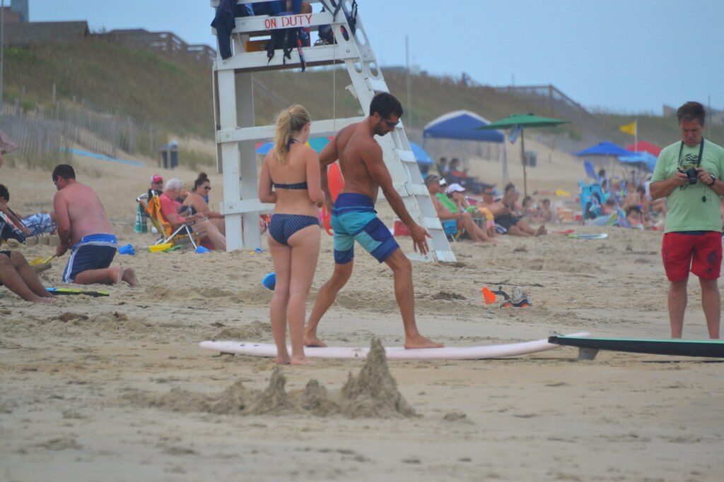 A group surf lesson on the sand — group size is one of the biggest price drivers